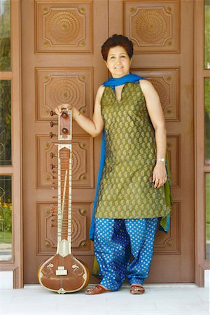 simsearch:630-01131008,k - Portrait of a mature woman standing in front of a closed wooden door and holding a sitar Foto de stock - Sin royalties Premium, Código: 630-01130661
