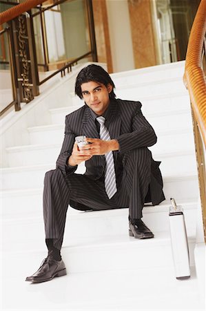 simsearch:630-02219583,k - Portrait of a businessman sitting on steps and holding a mobile phone Stock Photo - Premium Royalty-Free, Code: 630-01130769
