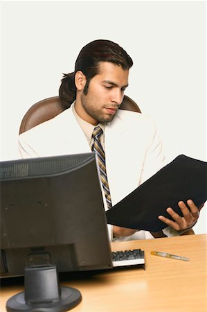 simsearch:630-01076251,k - Businessman reading a file in front of a computer Stock Photo - Premium Royalty-Free, Code: 630-01130909