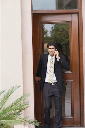 front door knob - Businessman talking on a mobile phone and smiling Stock Photo - Premium Royalty-Free, Code: 630-01130999