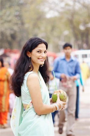 simsearch:630-01131029,k - Portrait d'une jeune femme tenant une noix de coco et souriant Photographie de stock - Premium Libres de Droits, Code: 630-01131029