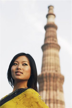 delhi monument - Low angle view of a young woman with a monument in the background Qutub Minar, Delhi, India Stock Photo - Premium Royalty-Free, Code: 630-01131064