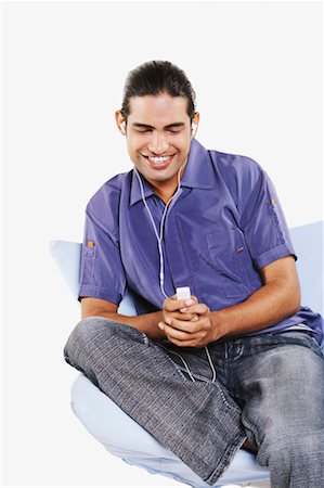 simsearch:630-01128257,k - Close-up of a young man sitting on a chair and listening to an MP3 player Stock Photo - Premium Royalty-Free, Code: 630-01131119