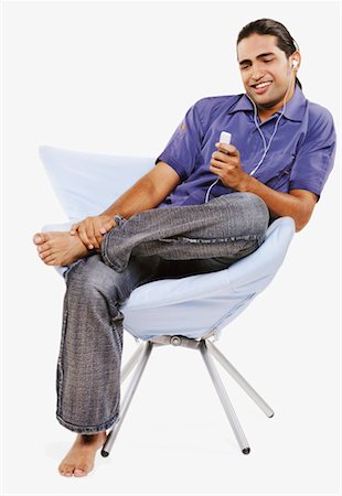 simsearch:630-01131178,k - Jeune homme assis sur une chaise et écouter un lecteur MP3 Photographie de stock - Premium Libres de Droits, Code: 630-01131178