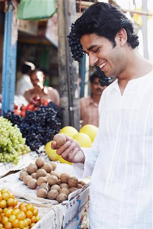 simsearch:630-01131029,k - Side profile of a young man standing at a fruit stand and holding a sapodilla Foto de stock - Royalty Free Premium, Número: 630-01131192