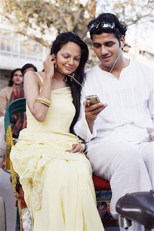 Young couple sitting in a rickshaw and listening to an MP3 player Stock Photo - Premium Royalty-Free, Code: 630-01131216