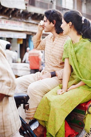 Side profile of a young couple sitting in a rickshaw and taking a photograph Stock Photo - Premium Royalty-Free, Code: 630-01131263