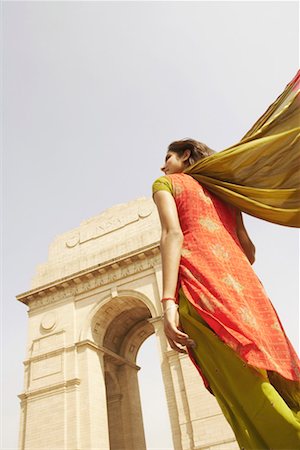 Low angle view of a young woman standing in front of a monument, India Gate, New Delhi, India Stock Photo - Premium Royalty-Free, Code: 630-01131288