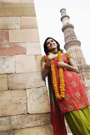 simsearch:630-01130737,k - Low angle view of a young woman leaning against a wall and smiling Stock Photo - Premium Royalty-Free, Code: 630-01131377