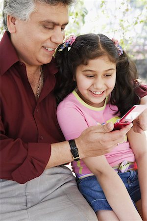 Close-up of a mature man and his grandchildren looking at a mobile phone Stock Photo - Premium Royalty-Free, Code: 630-01131532