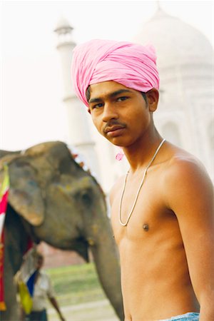 Close-up of a young man standing in front of an elephant, Taj Mahal, Agra, Uttar Pradesh, India Stock Photo - Premium Royalty-Free, Code: 630-01131558