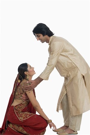 Side profile of a young woman touching feet of her husband on a traditional festival Stock Photo - Premium Royalty-Free, Code: 630-01191976