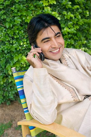 Young man talking on a mobile phone and smiling Stock Photo - Premium Royalty-Free, Code: 630-01192244