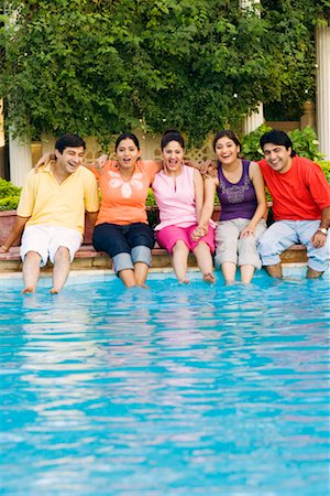 Three young women with two young men sitting at the poolside Stock Photo - Premium Royalty-Free, Code: 630-01192364