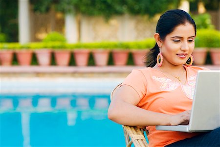 Close-up of a young woman using a laptop at the poolside Stock Photo - Premium Royalty-Free, Code: 630-01192360