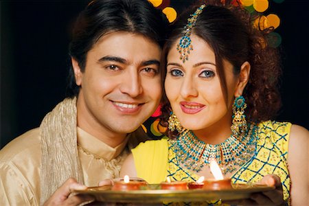 Portrait of a young couple holding a plate of religious offerings and smiling Stock Photo - Premium Royalty-Free, Code: 630-01192396