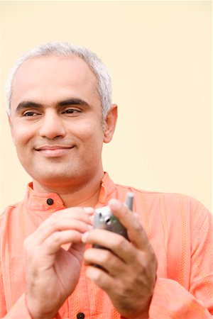 Close-up of a mid adult man holding a mobile phone and smiling Stock Photo - Premium Royalty-Free, Code: 630-01192452