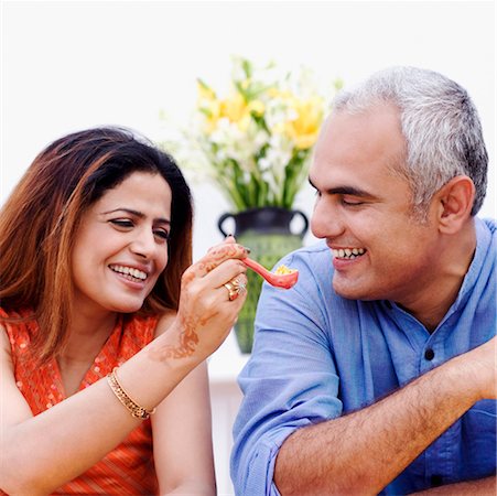 Mid adult woman feeding a spoonful of snacks to a mid adult man Stock Photo - Premium Royalty-Free, Code: 630-01192638