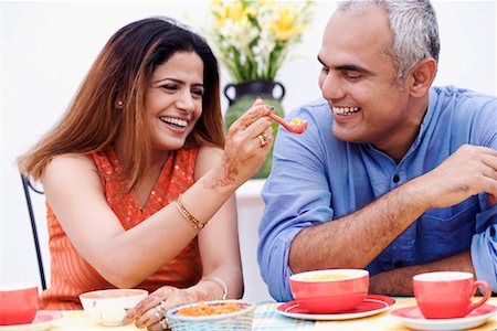 simsearch:655-03457904,k - Mid adult woman feeding a spoonful of snacks to a mid adult man Stock Photo - Premium Royalty-Free, Code: 630-01192639