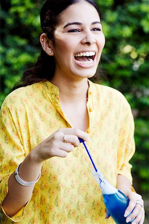 Close-up of a young woman holding a bubble wand and a bottle of liquid soap Stock Photo - Premium Royalty-Free, Code: 630-01192665