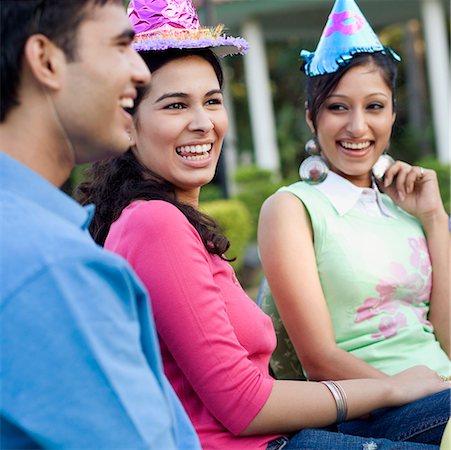 Two young women and a young man smiling at a birthday party Stock Photo - Premium Royalty-Free, Code: 630-01192707