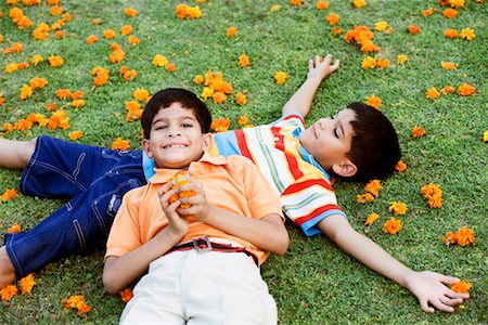 High angle view of a boy lying on the grass with his brother resting his head on his abdomen Foto de stock - Sin royalties Premium, Código: 630-01192722