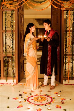 standing rangoli images - Young couple holding oil lamps in a plate Stock Photo - Premium Royalty-Free, Code: 630-01192773