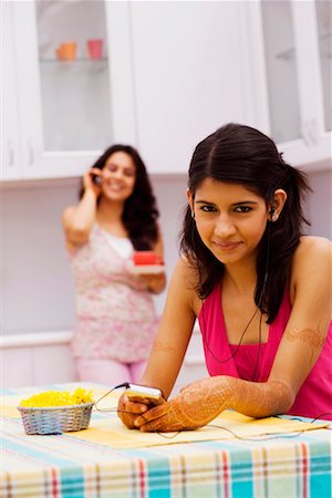 simsearch:630-01079908,k - Portrait of a young woman listening to music with a mid adult woman talking on a mobile phone in the background Stock Photo - Premium Royalty-Free, Code: 630-01192840