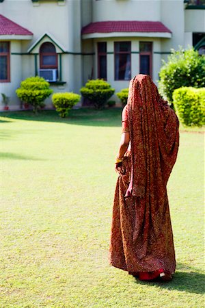 Rear view of a bride in traditional wedding dress walking in a lawn Stock Photo - Premium Royalty-Free, Code: 630-01192978