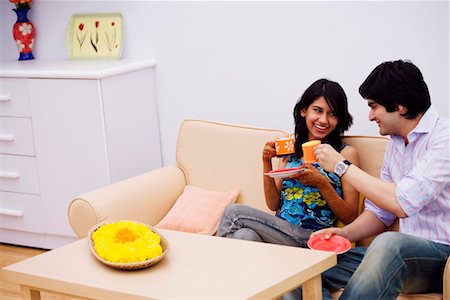 Young couple sitting on a couch and holding cups of tea Stock Photo - Premium Royalty-Free, Code: 630-01192971