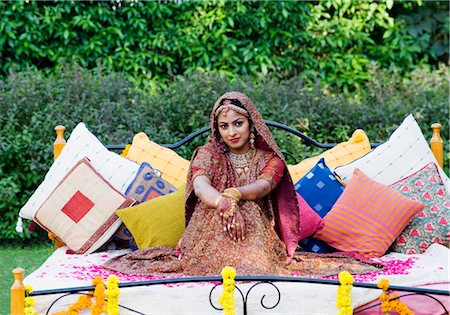 Portrait of a bride in a traditional wedding dress sitting on the bed in a lawn Stock Photo - Premium Royalty-Free, Code: 630-01192992