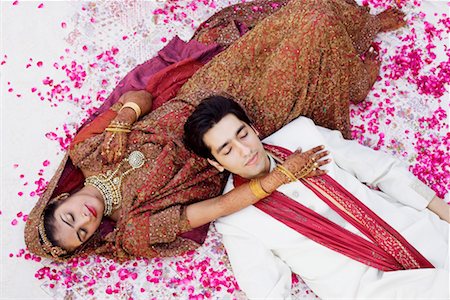 High angle view of a newlywed couple in traditional wedding outfits sleeping on the bed Stock Photo - Premium Royalty-Free, Code: 630-01193004