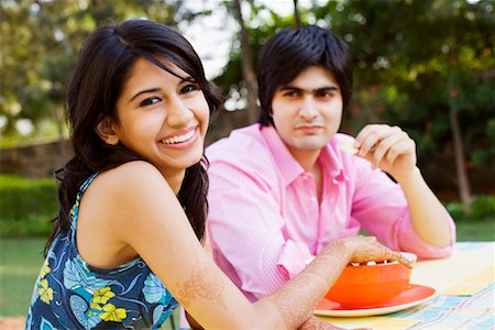 simsearch:655-03457904,k - Portrait of a young woman sitting at a table and smiling with a young man sitting beside her Stock Photo - Premium Royalty-Free, Code: 630-01193008