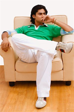 Young man sitting in an armchair Stock Photo - Premium Royalty-Free, Code: 630-01297007