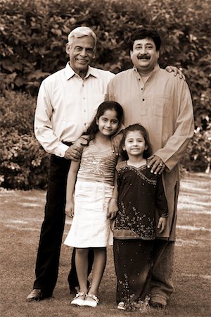 Portrait of a senior man with his son and two granddaughters standing in a garden and smiling Stock Photo - Premium Royalty-Free, Code: 630-01297033