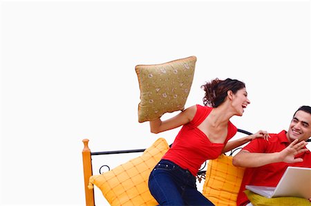 Young woman swinging a cushion at a young man Stock Photo - Premium Royalty-Free, Code: 630-01297130