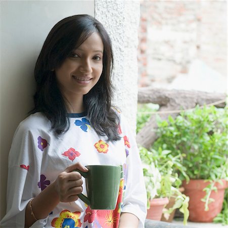 simsearch:630-01491487,k - Portrait of a young woman holding a cup of coffee and smiling Fotografie stock - Premium Royalty-Free, Codice: 630-01490463