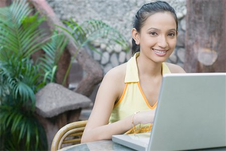 Portrait of a young woman using a laptop and smiling Stock Photo - Premium Royalty-Free, Code: 630-01490478