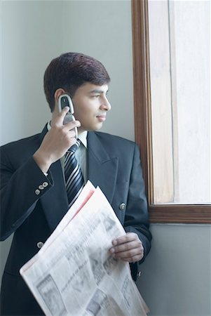 Businessman talking on a mobile phone and holding a newspaper Stock Photo - Premium Royalty-Free, Code: 630-01490490