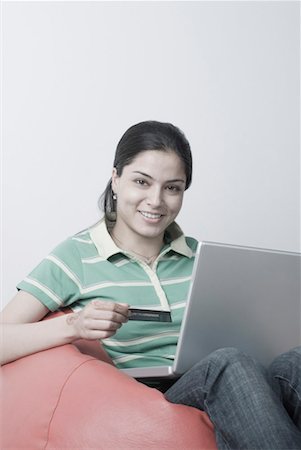 simsearch:630-06722636,k - Portrait of a young woman holding a credit card and using a laptop Foto de stock - Sin royalties Premium, Código: 630-01490504