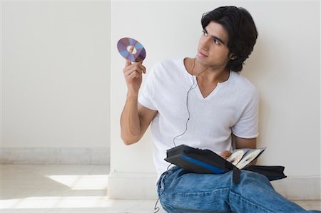 earbuds jeans - Young man listening to music and holding a CD Stock Photo - Premium Royalty-Free, Code: 630-01490826