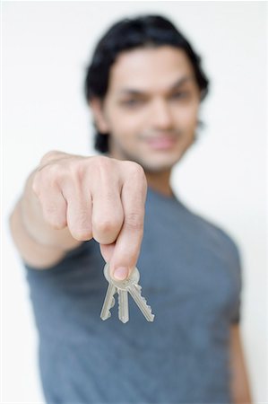 fiore - Close-up of a young man showing three keys and smiling Stock Photo - Premium Royalty-Free, Code: 630-01490897