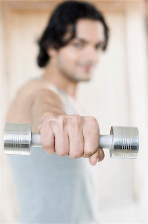 Close-up of a young man exercising with a dumbbell Stock Photo - Premium Royalty-Free, Code: 630-01490891