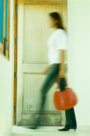 simsearch:630-01709905,k - Side profile of a young woman carrying a hand bag and walking out of a room Stock Photo - Premium Royalty-Free, Code: 630-01490926