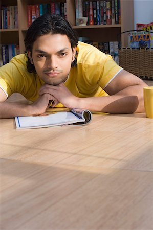 Portrait of a young man lying on the floor of a library and thinking Stock Photo - Premium Royalty-Free, Code: 630-01490981