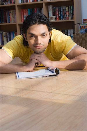 Portrait of a young man lying on the floor of a library and thinking Stock Photo - Premium Royalty-Free, Code: 630-01490982