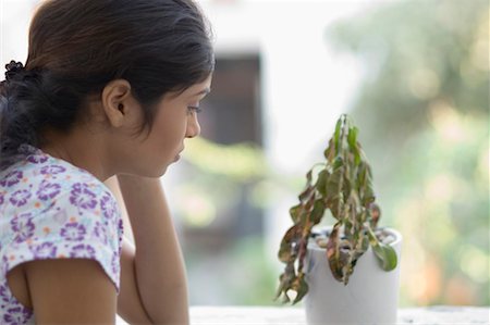 sad indian woman images - Side profile of a young woman looking at a dried plant Stock Photo - Premium Royalty-Free, Code: 630-01491001