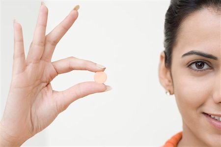 Portrait of a young woman holding a pill Stock Photo - Premium Royalty-Free, Code: 630-01491207