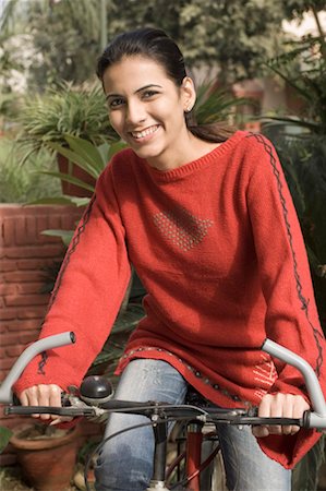 fiore - Portrait of a young woman sitting on a bicycle and smiling Stock Photo - Premium Royalty-Free, Code: 630-01491231