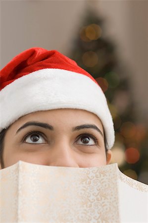 santa clauses for cards - Close-up of a young woman wearing a Santa hat in front of a greeting card Stock Photo - Premium Royalty-Free, Code: 630-01491255
